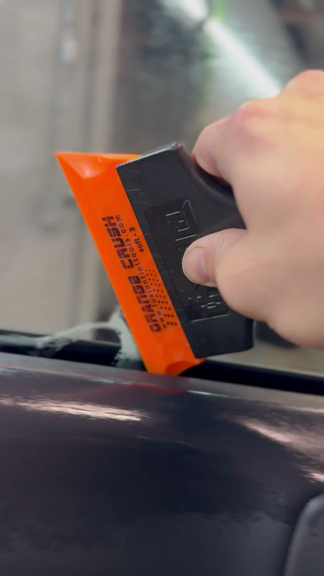Technician tinting a car window with a clean edge-setting motion.